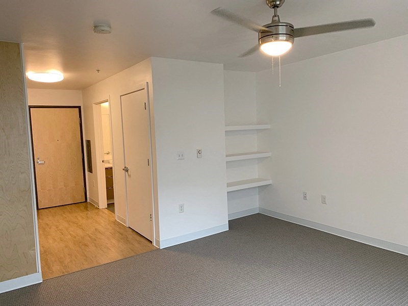 a bedroom with white walls and a ceiling fan