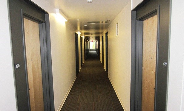 a long hallway with black doors and white walls