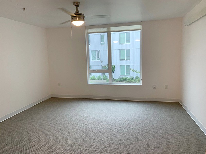 an empty room with a window and a ceiling fan