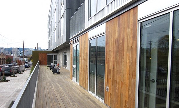 the side of a building with glass windows and a wooden sidewalk