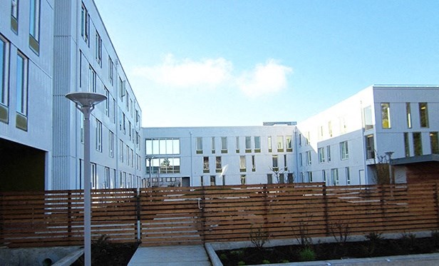 a row of new apartment buildings with a wooden fence