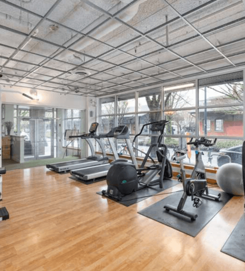 A gym with wooden floors and various exercise equipment.
