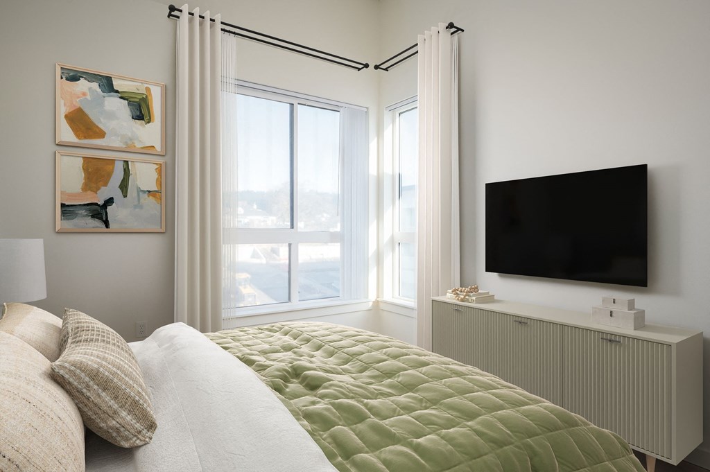 A bedroom with a bed, a television, and two paintings on the wall.