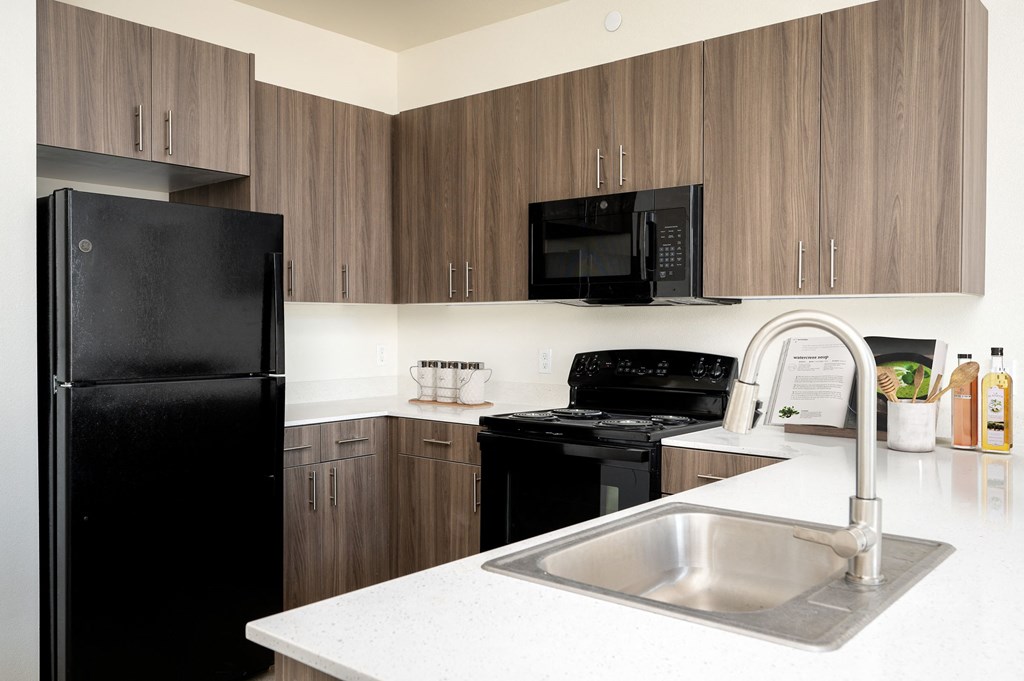 A kitchen with a black refrigerator and a black microwave.