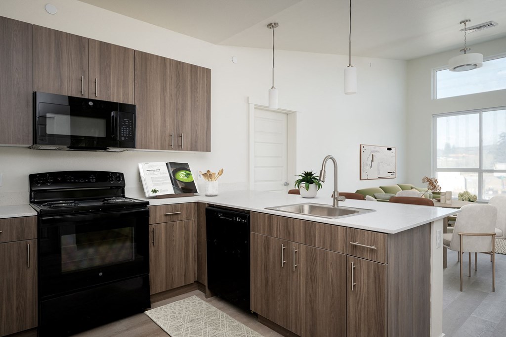 A modern kitchen with a black oven and microwave, wooden cabinets, and a white countertop.
