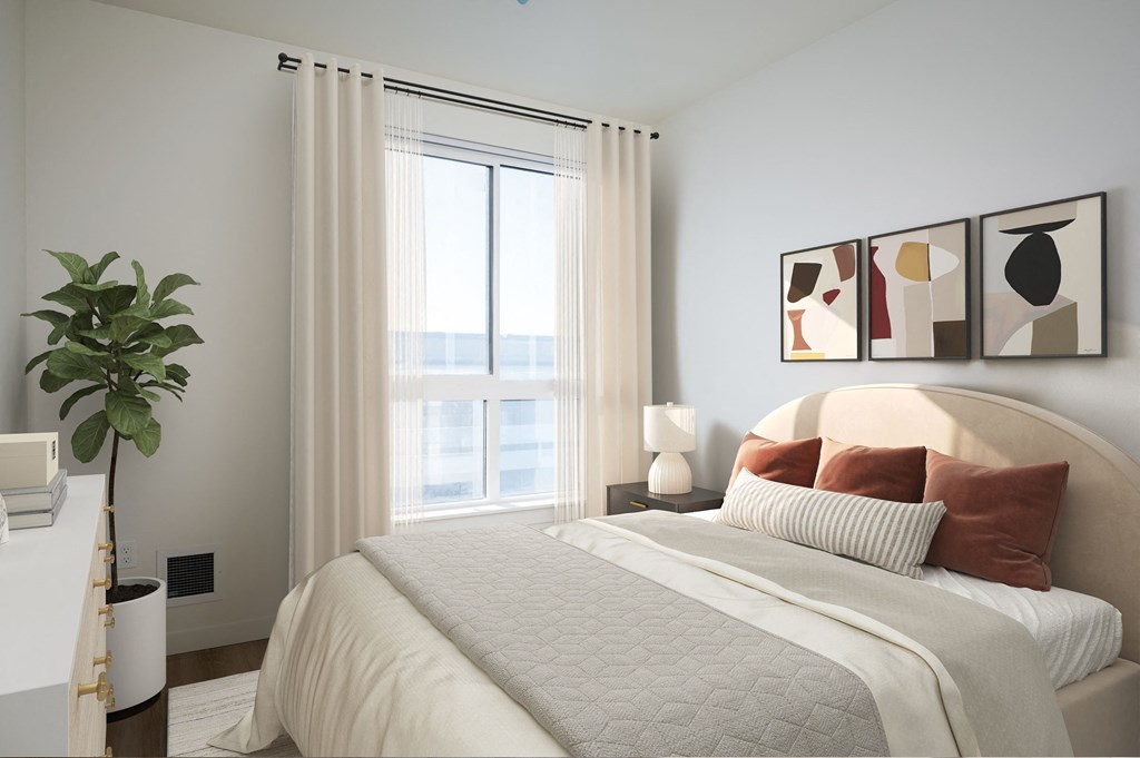 A bedroom with a large bed, a potted plant, and a window with curtains.