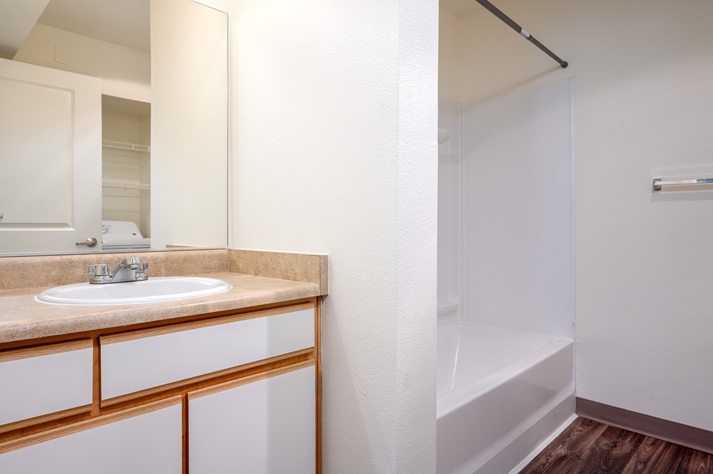 A bathroom with a sink, mirror, and wooden cabinet.