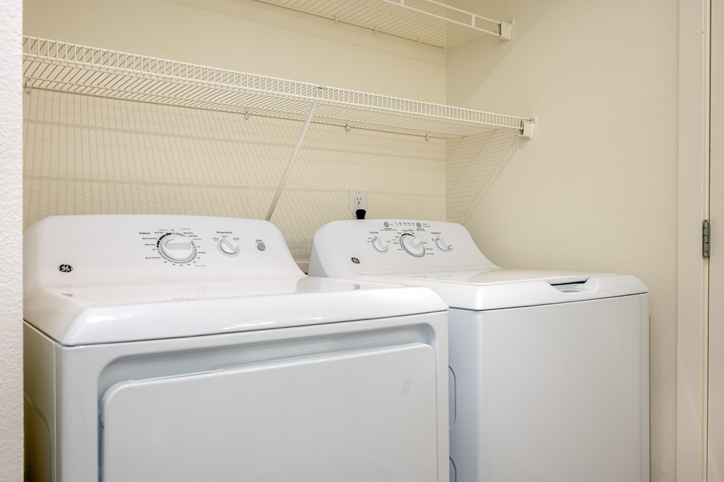 Two white front loading washing machines in a laundry room.