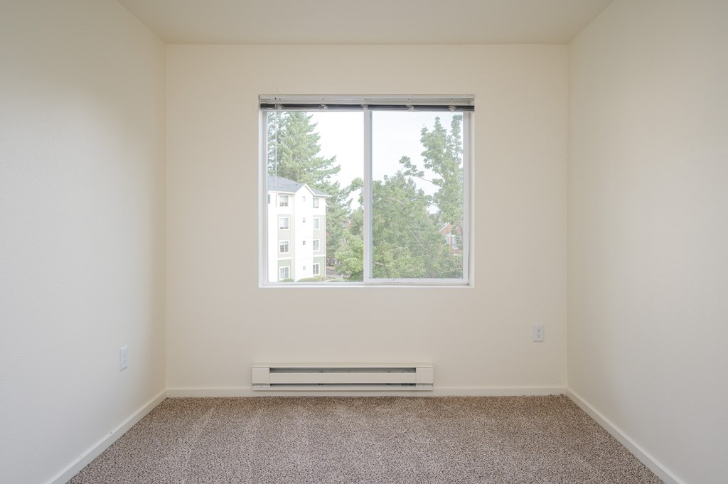A room with a window and a heater on the floor.
