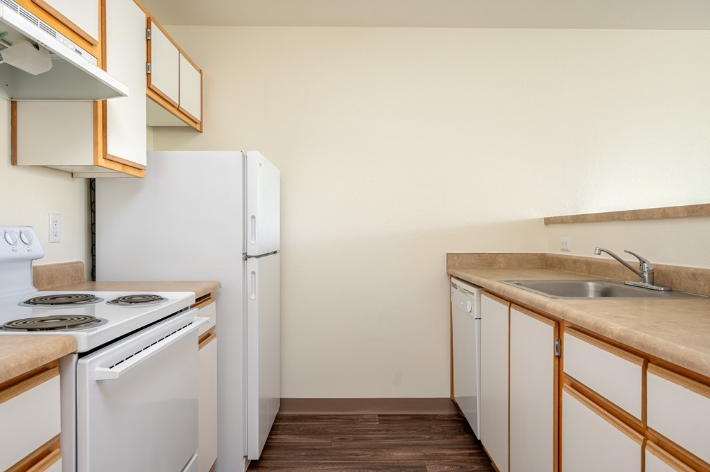 A kitchen with white appliances and wooden cabinets.