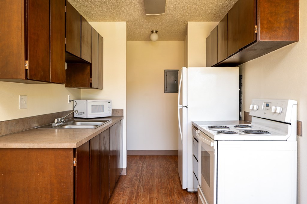 A kitchen with white appliances and wooden cabinets.