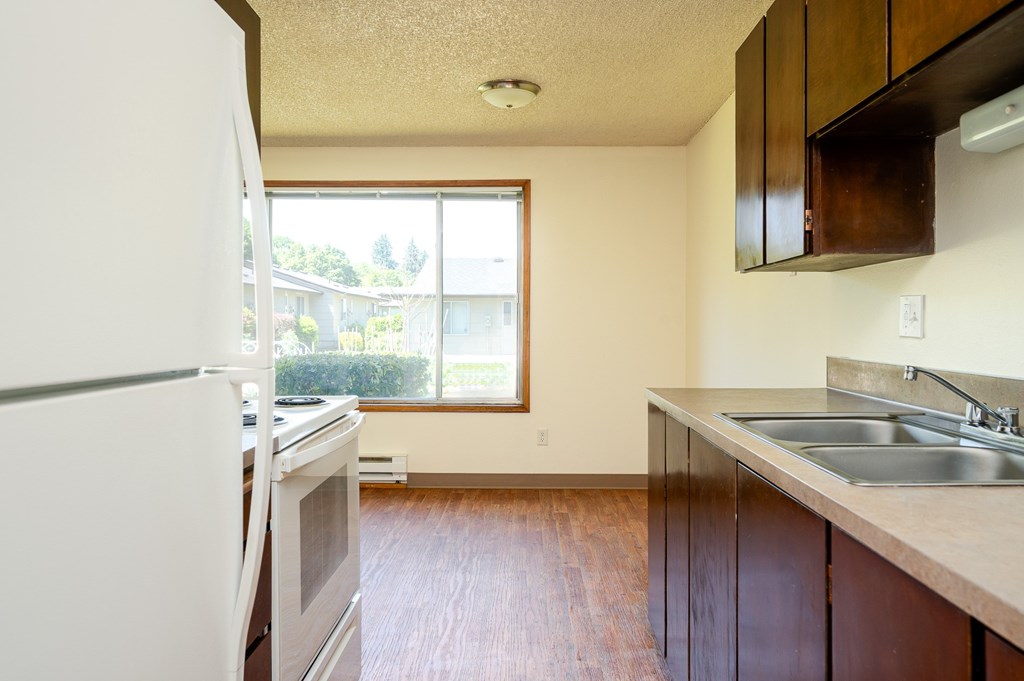 A kitchen with a white fridge and brown cabinets.