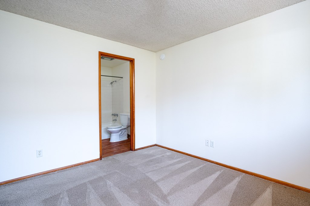 A bathroom with a toilet and a mirror is visible through the door.