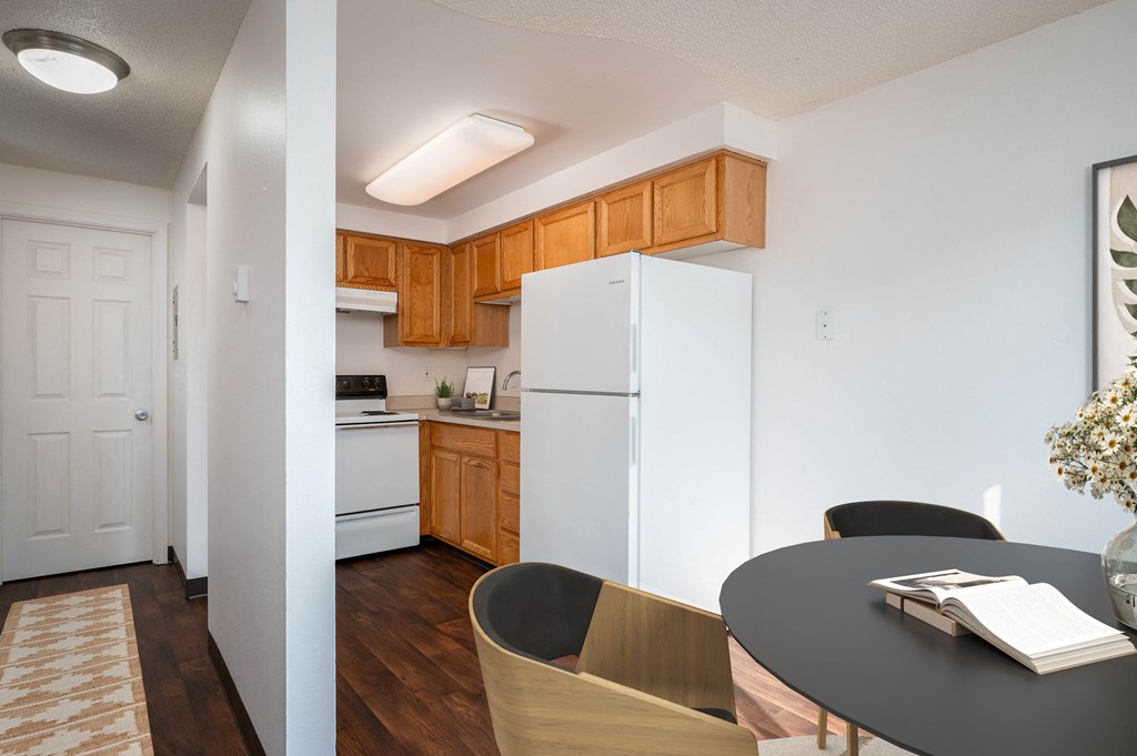 a kitchen with white appliances and wooden cabinets and a dining room table