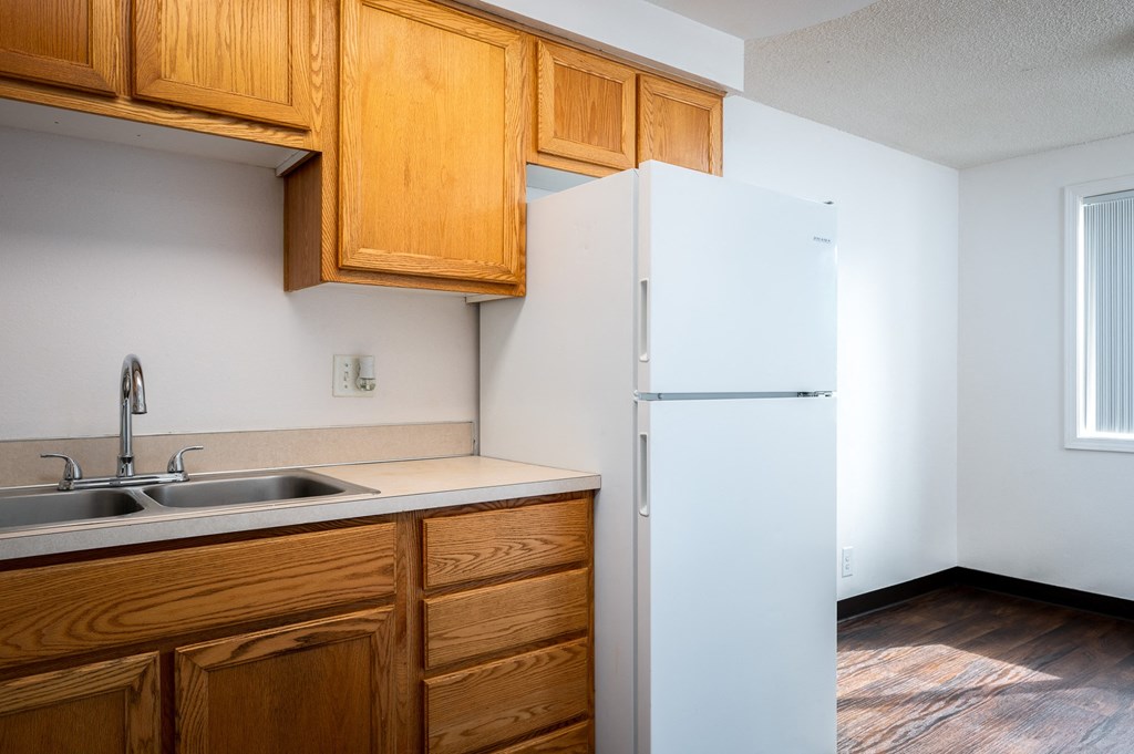 an empty kitchen with a white refrigerator and wooden cabinets