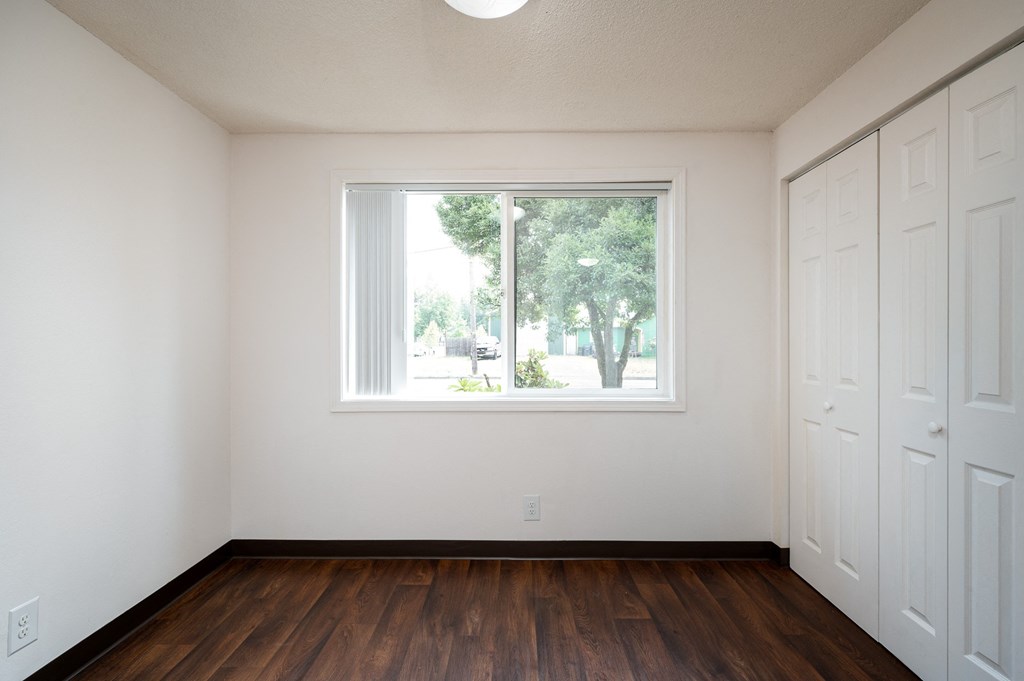 an empty room with a large window and wooden floors