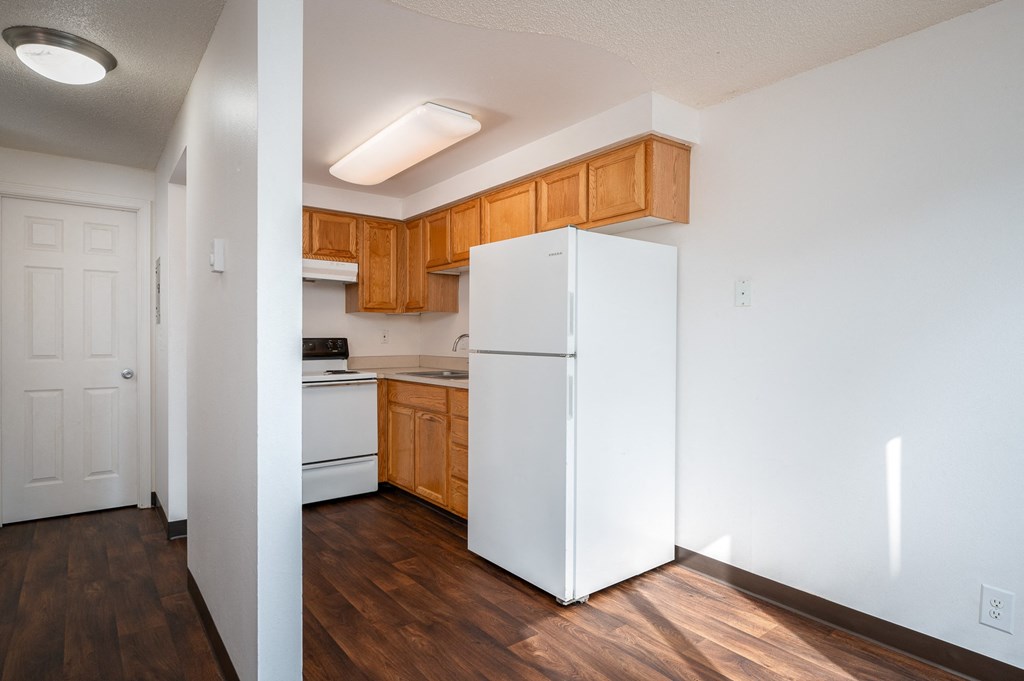 an empty kitchen with a white refrigerator and wooden cabinets
