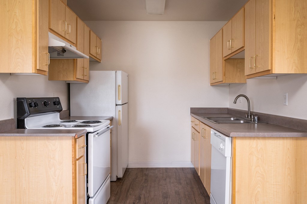 an empty kitchen with wood cabinets and white appliances