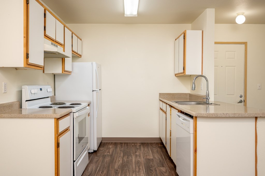 A kitchen with white appliances and wooden cabinets.