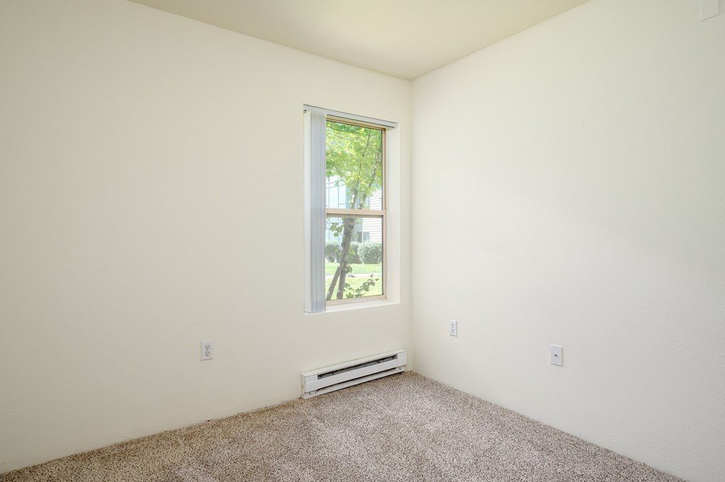 A room with a window and carpeted floor.