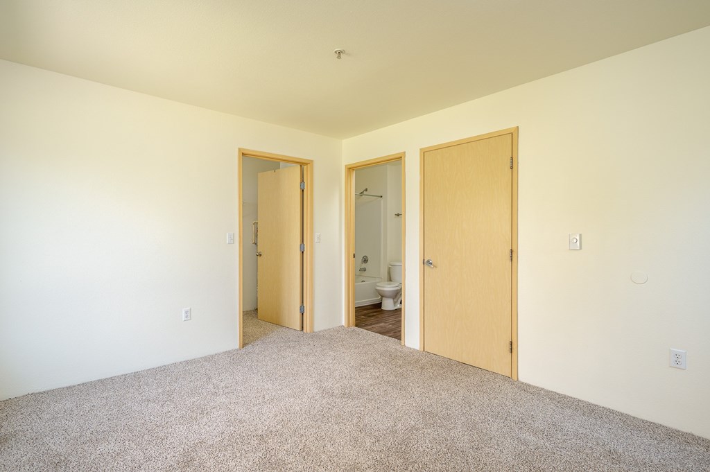 A room with a carpeted floor and three doors.