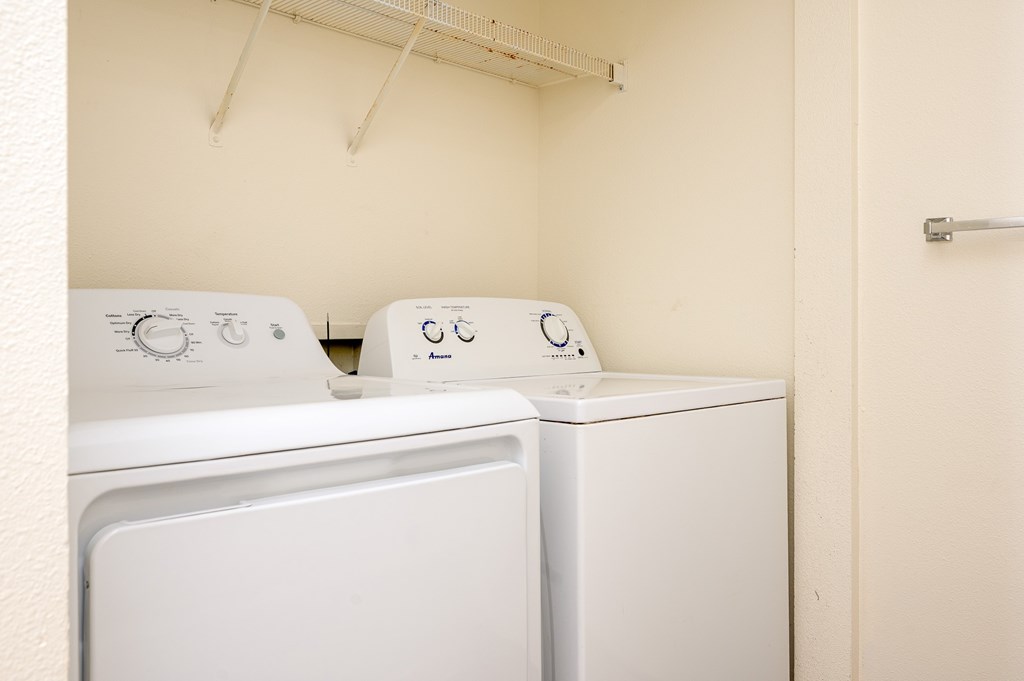 Two white front loading washing machines in a small laundry room.