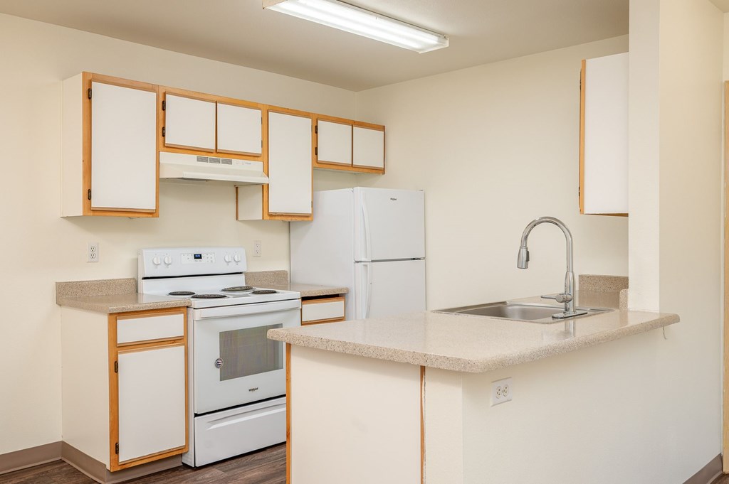 A kitchen with white appliances and wooden cabinets.