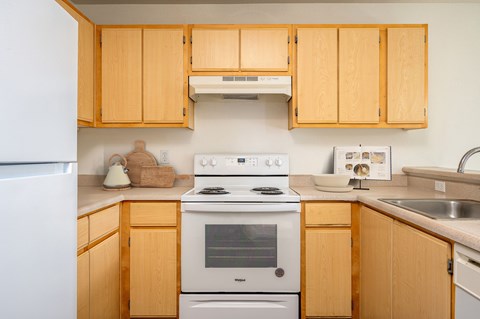 A kitchen with wooden cabinets and a white stove top oven.