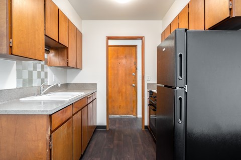 a kitchen with a black refrigerator and wooden cabinets