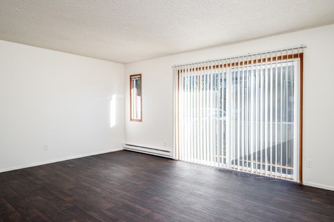an empty living room with a large window and wood flooring