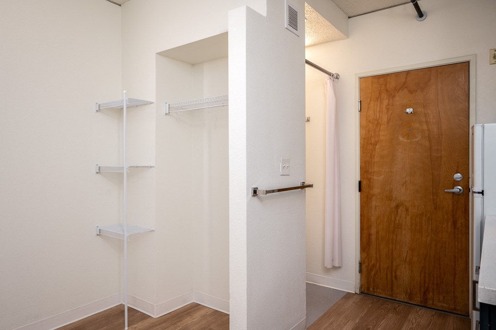 a walk in closet in a bedroom with a wooden door and white walls