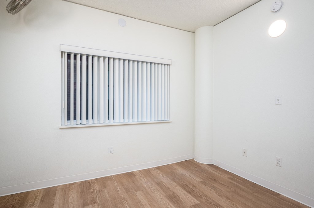 a bedroom with a large window and hardwood floors