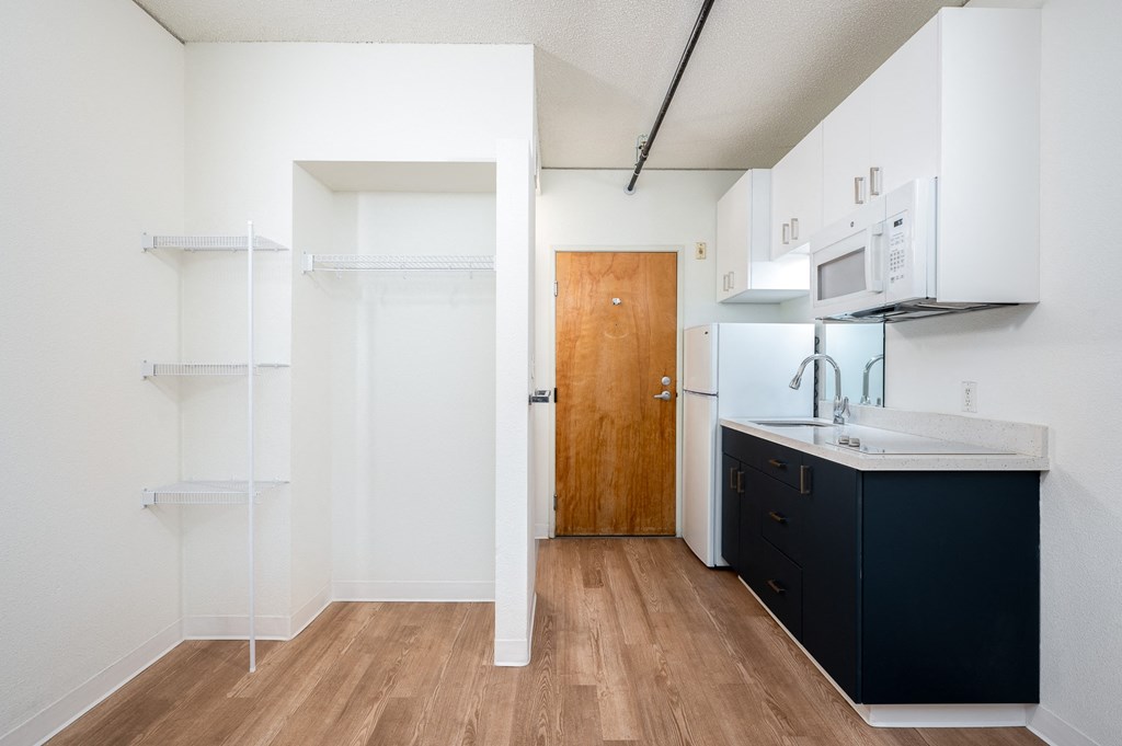 a kitchen with white walls and a wooden floor