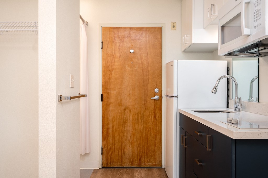 a kitchen in a small apartment with a wooden door and white appliances