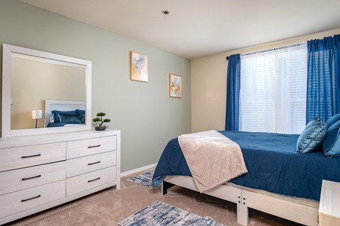 A bedroom with a bed, dresser, and mirror.