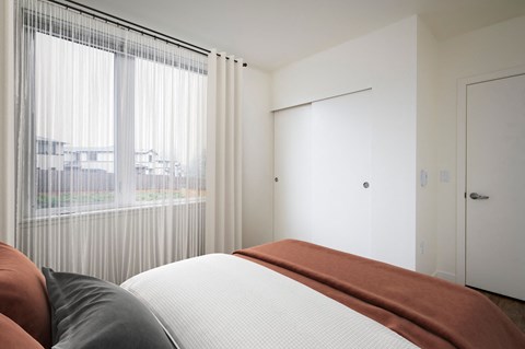 A bedroom with a large bed and a view of the city through the window.