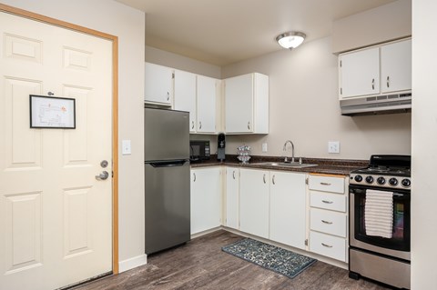 A kitchen with white cabinets and a stainless steel refrigerator.