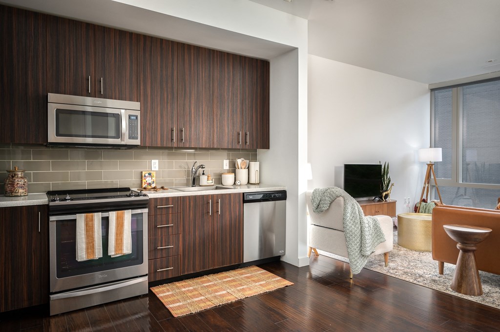 a kitchen and living room with wooden cabinets and stainless steel appliances