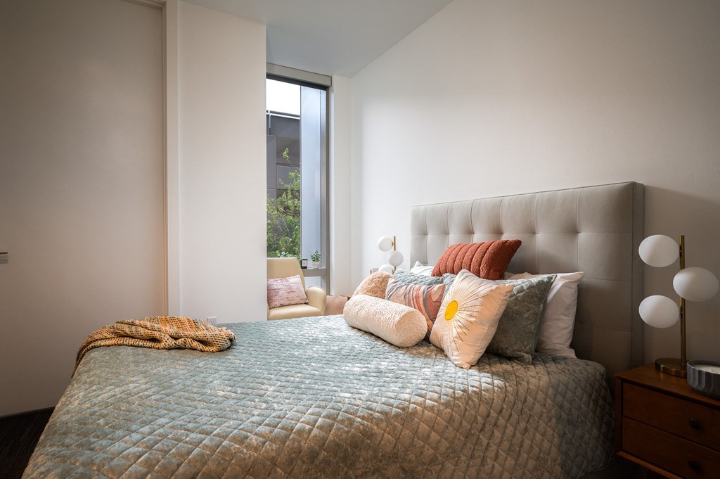 a bedroom with a bed and pillows and a window