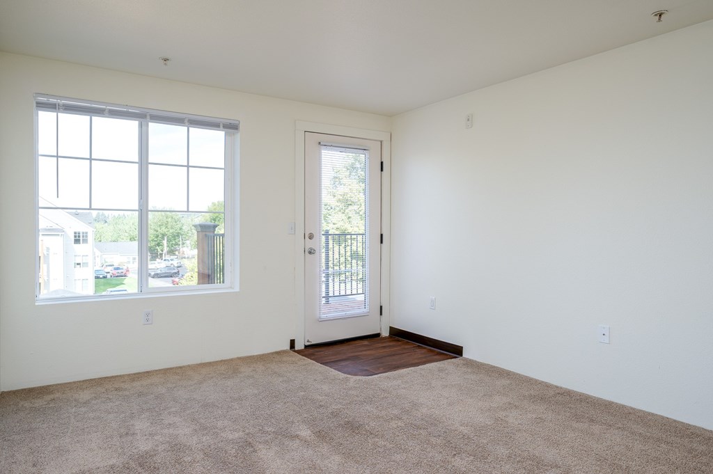 A room with a door, window and carpet.