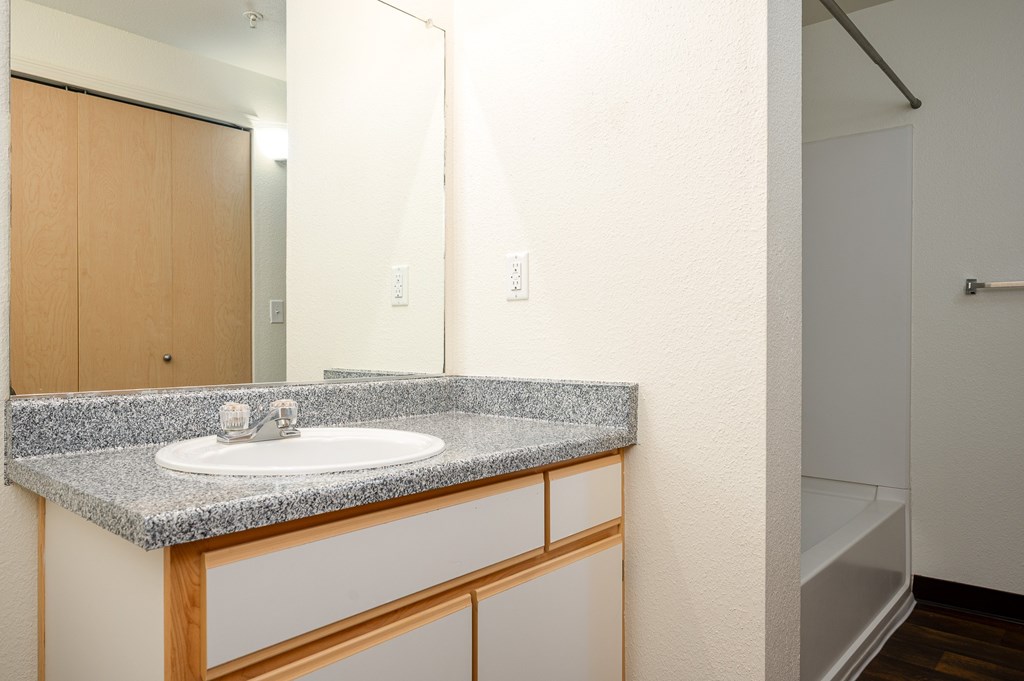 A bathroom with a granite countertop and a white sink.