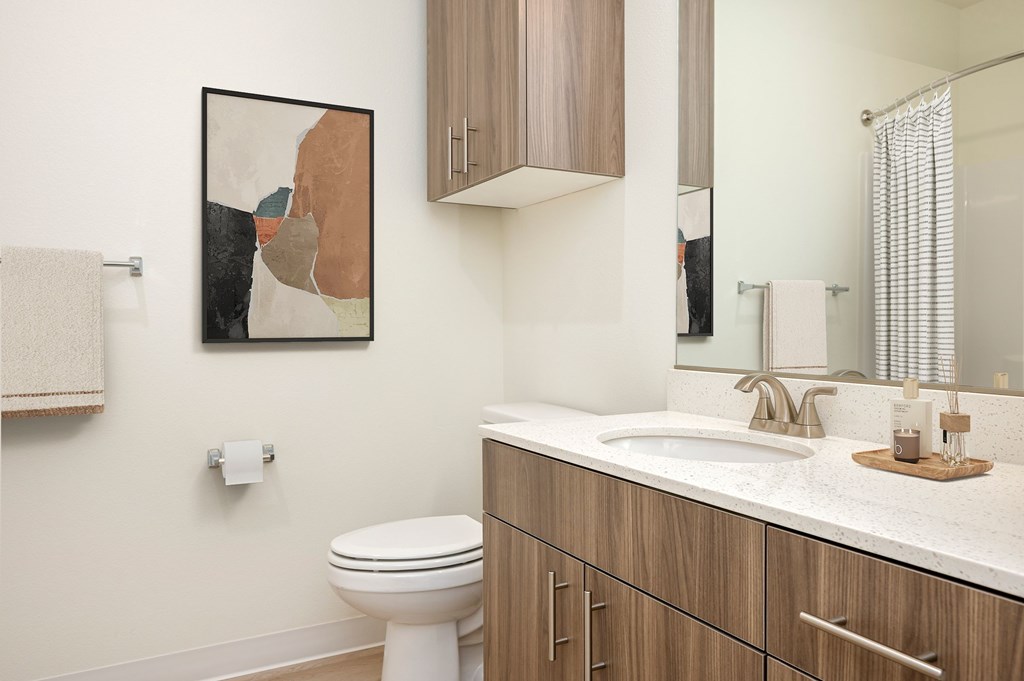 A bathroom with a toilet, sink, and a painting on the wall.