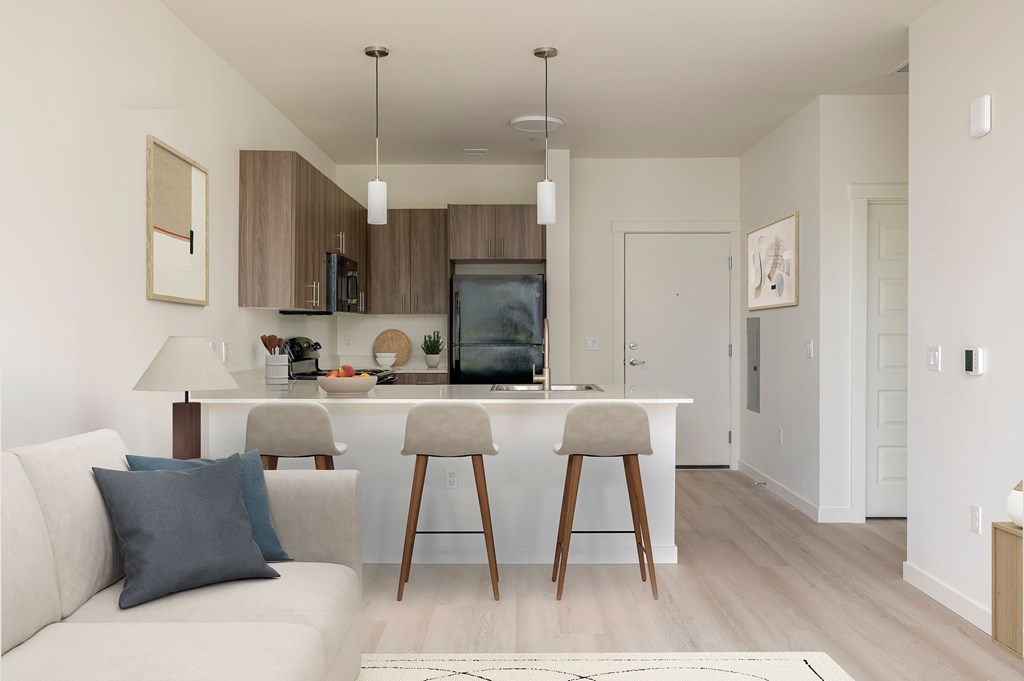 A modern kitchen with a white couch and wooden bar stools.