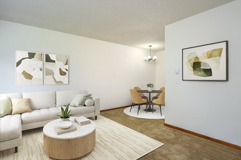 A living room with a white couch, a coffee table, and a dining table with chairs.