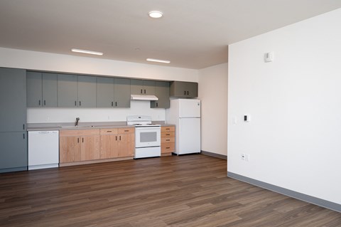 an empty kitchen with white appliances and wood floors