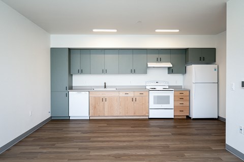 an empty kitchen with white appliances and wood floors