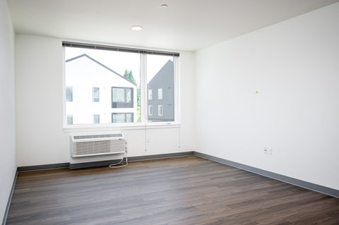 an empty living room with a large window and wooden floors