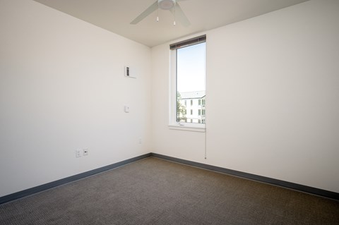 an empty room with a window and a ceiling fan