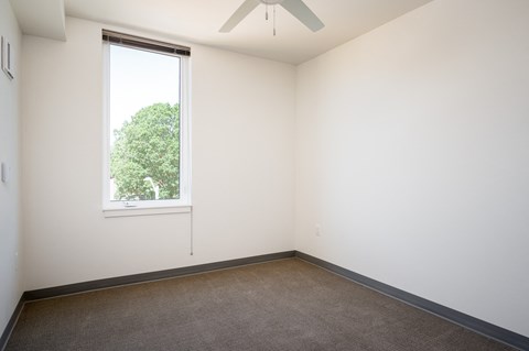 an empty room with a window and a ceiling fan