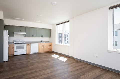 an empty kitchen with white appliances and wood flooring